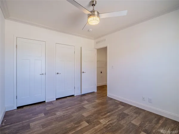 a view of an empty room with chandelier fan and wooden floor