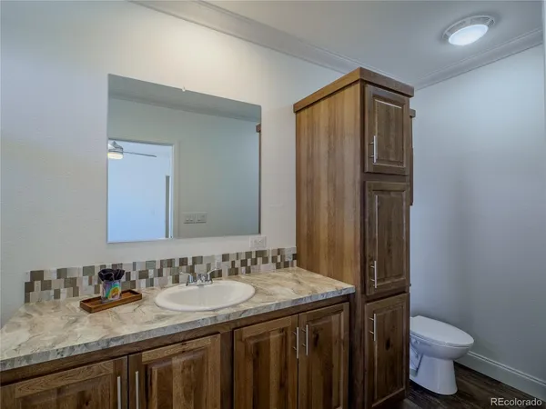 a bathroom with a granite countertop sink toilet and mirror