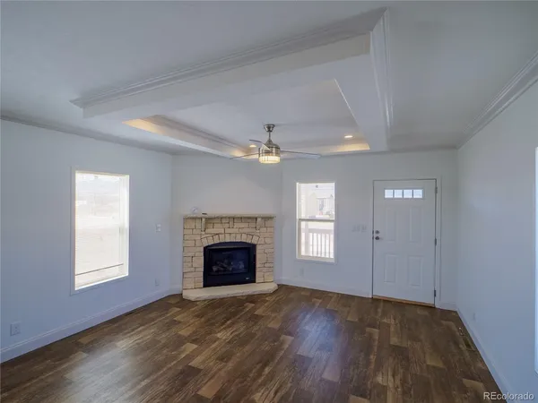 an empty room with windows fireplace and wooden floor