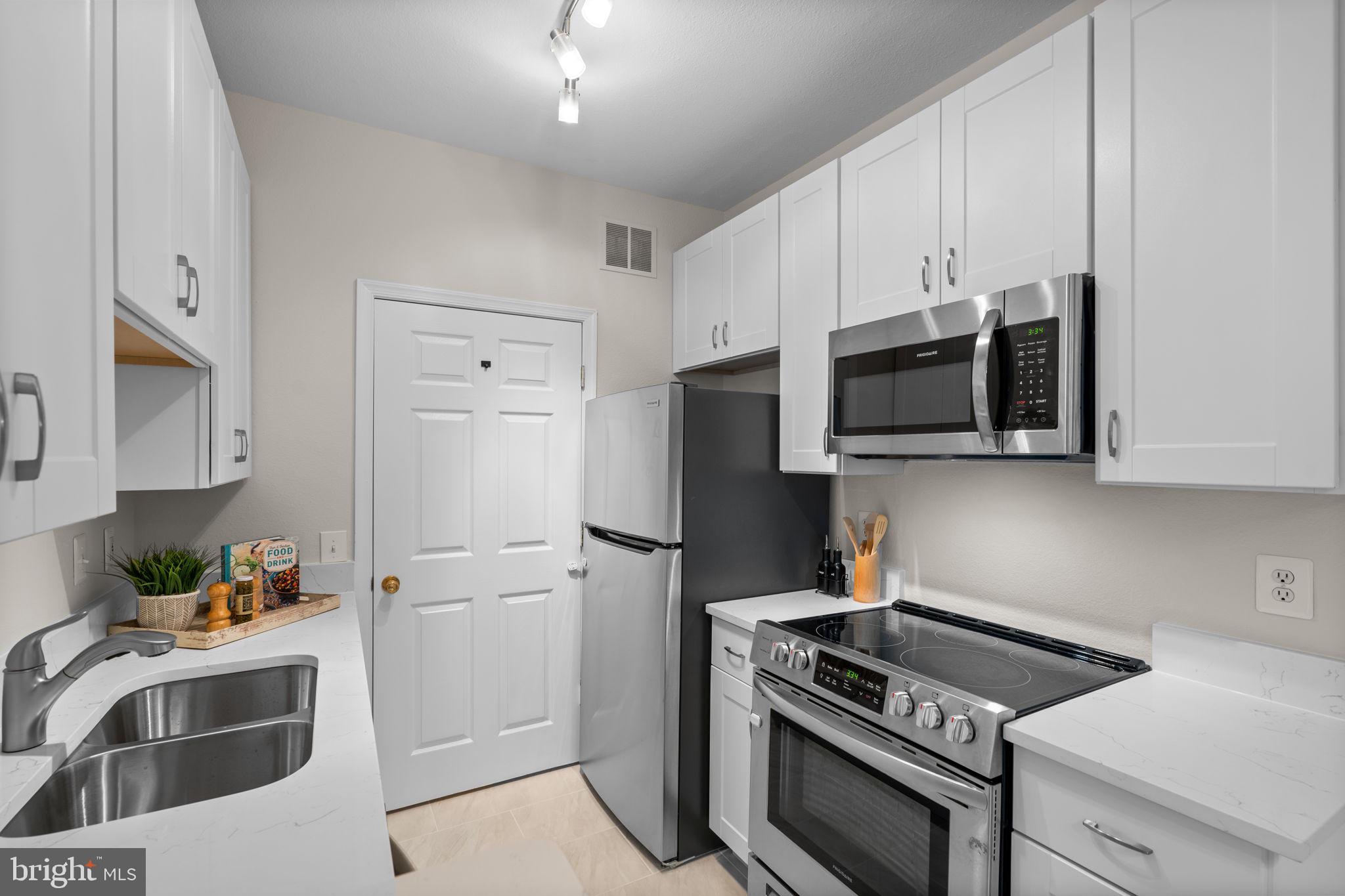 1570 Spring Gate Dr., Unit 7303 McLean, VA 22102 - Photo 12 of 25 a kitchen with stainless steel appliances a stove a microwave and a sink