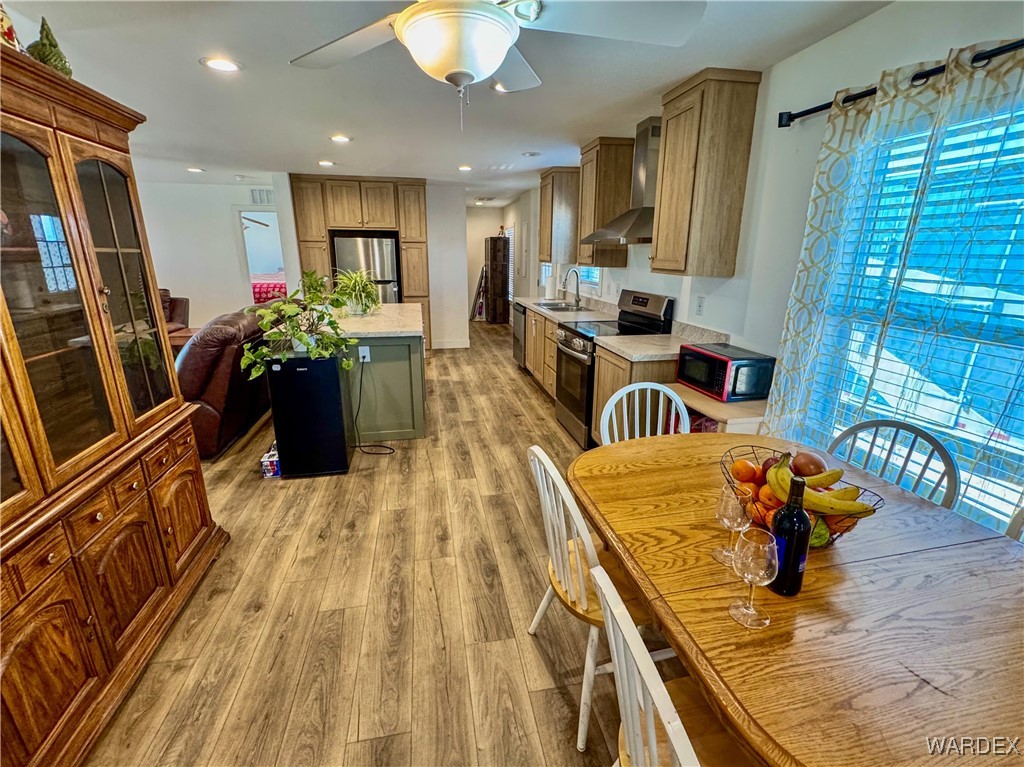 15333 South Doc Holliday Road Yucca, AZ 86438 - Photo 2 of 15 Kitchen with stainless steel appliances, light countertops, a sink, light wood-type flooring, and wall chimney exhaust hood