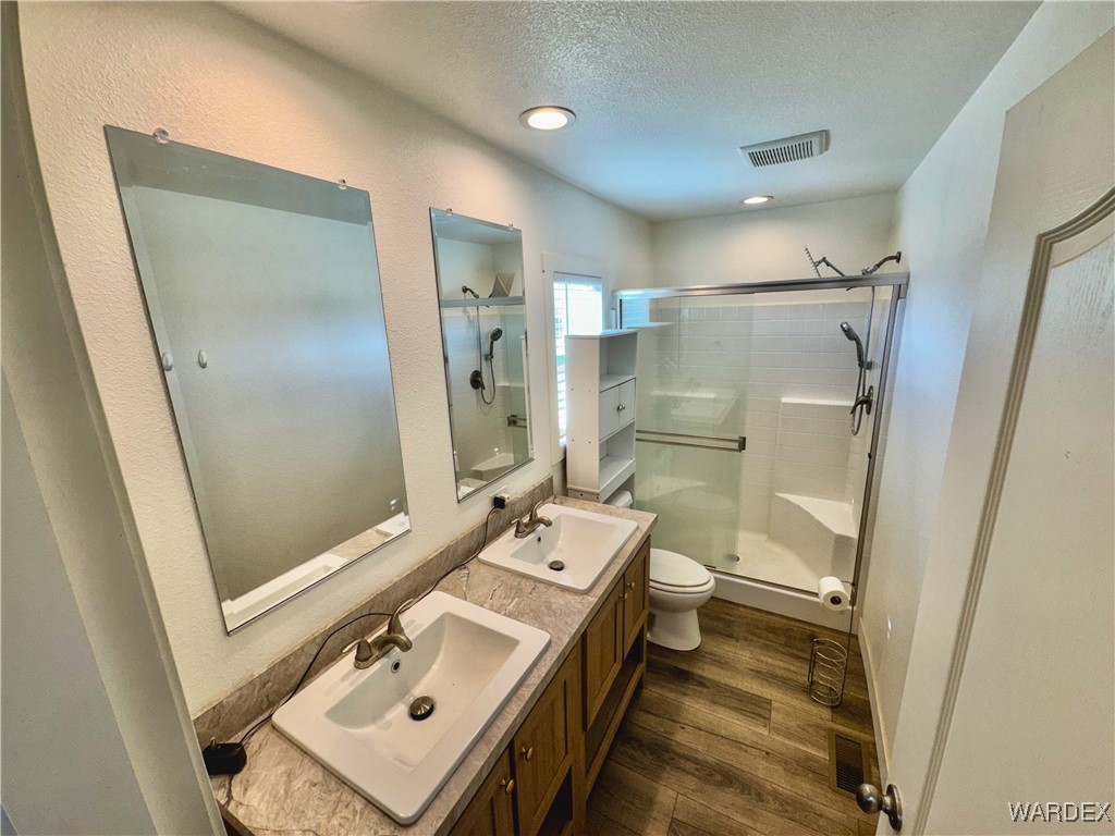 15333 South Doc Holliday Road Yucca, AZ 86438 - Photo 5 of 15 Full bathroom with visible vents, a stall shower, a sink, a textured ceiling, and wood finished floors