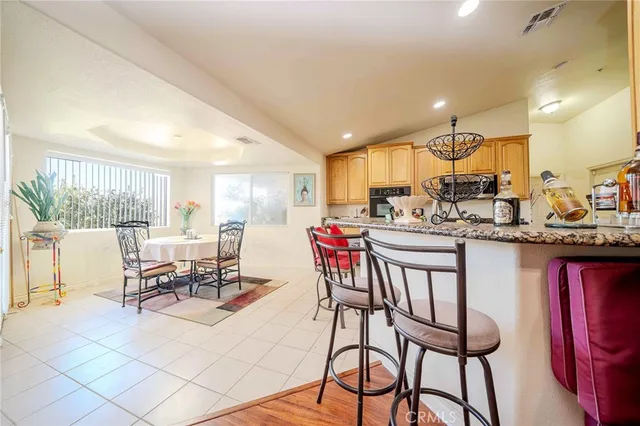 a dining hall with stainless steel appliances kitchen island granite countertop a dining table and chairs