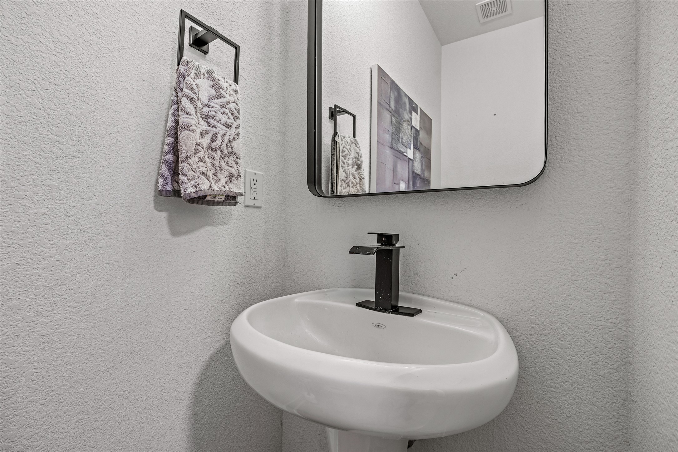1408 Homespun Road Austin, TX 78745 - Photo 12 of 20 A chic pedestal sink with a contemporary black faucet complements the minimalist aesthetic of this well-appointed bathroom.