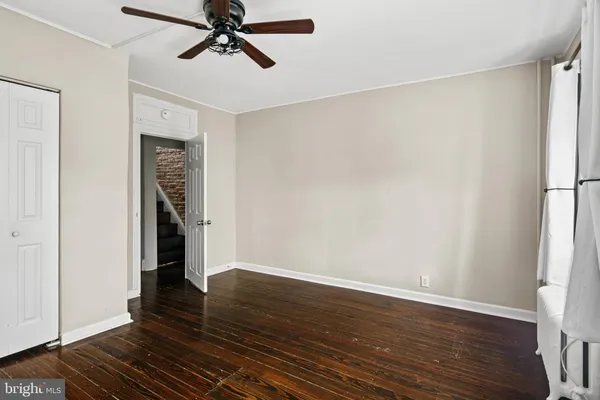 an empty room with wooden floor closet and windows