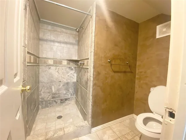 a bathroom with a granite countertop shower a toilet and a sink