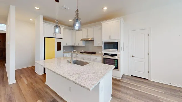 a kitchen with kitchen island a sink stainless steel appliances and white cabinets