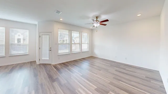 a view of empty room with wooden floor and fan