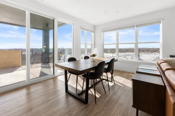 a dining room with wooden floor a chandelier a glass table and chairs