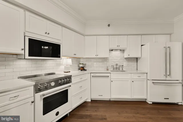 a kitchen with stainless steel appliances white cabinets and wooden floors