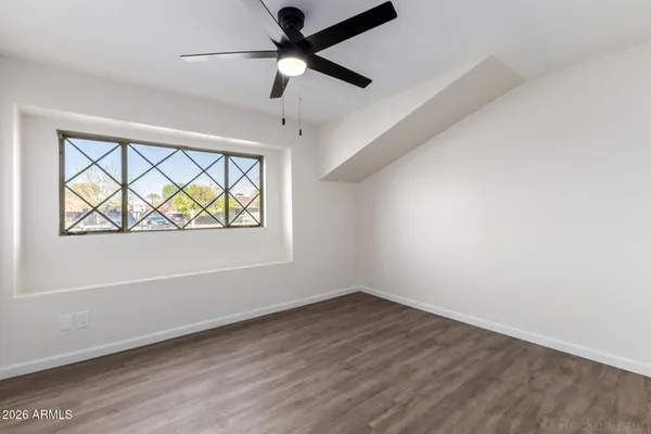 an empty room with wooden floor ceiling fan and windows