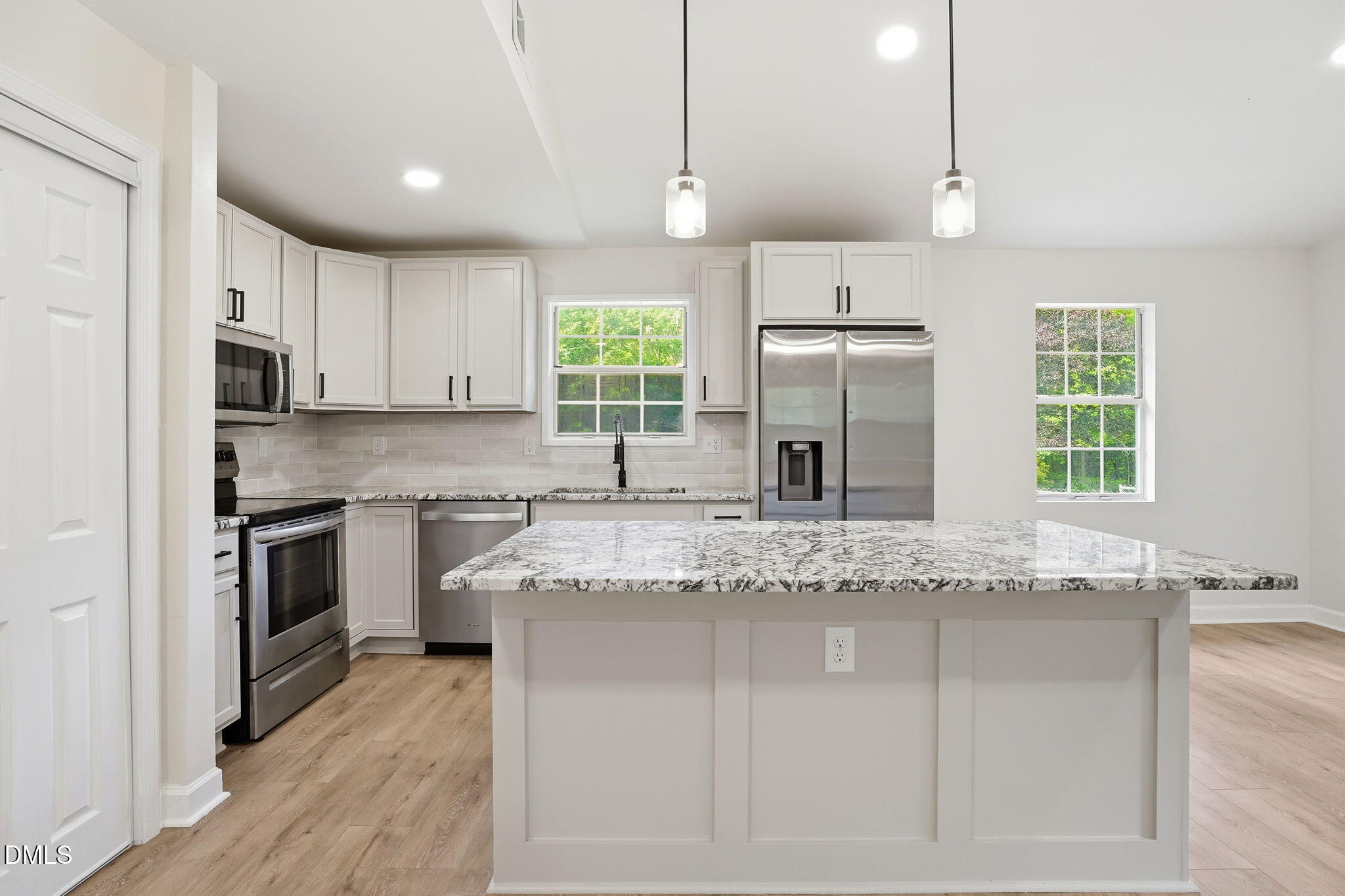 3602 Harrison Road Castalia, NC 27816 - Photo 34 of 48 a kitchen with kitchen island granite countertop a stove a sink and white cabinets with wooden floor