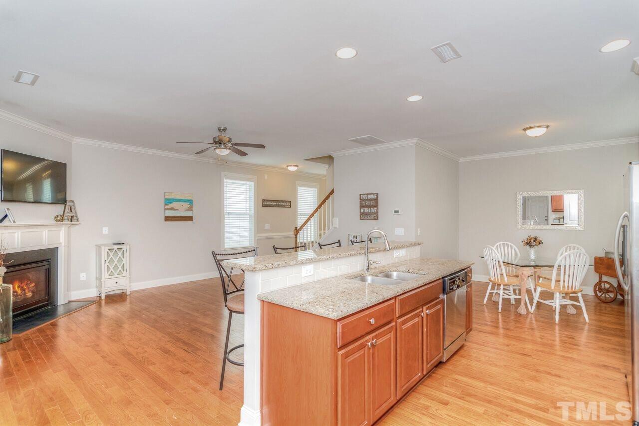 1141 Chapanoke Road Raleigh, NC 27603 - Photo 11 of 25 a living room with stainless steel appliances granite countertop a kitchen island a stove a sink a dining table and chairs with wooden floor