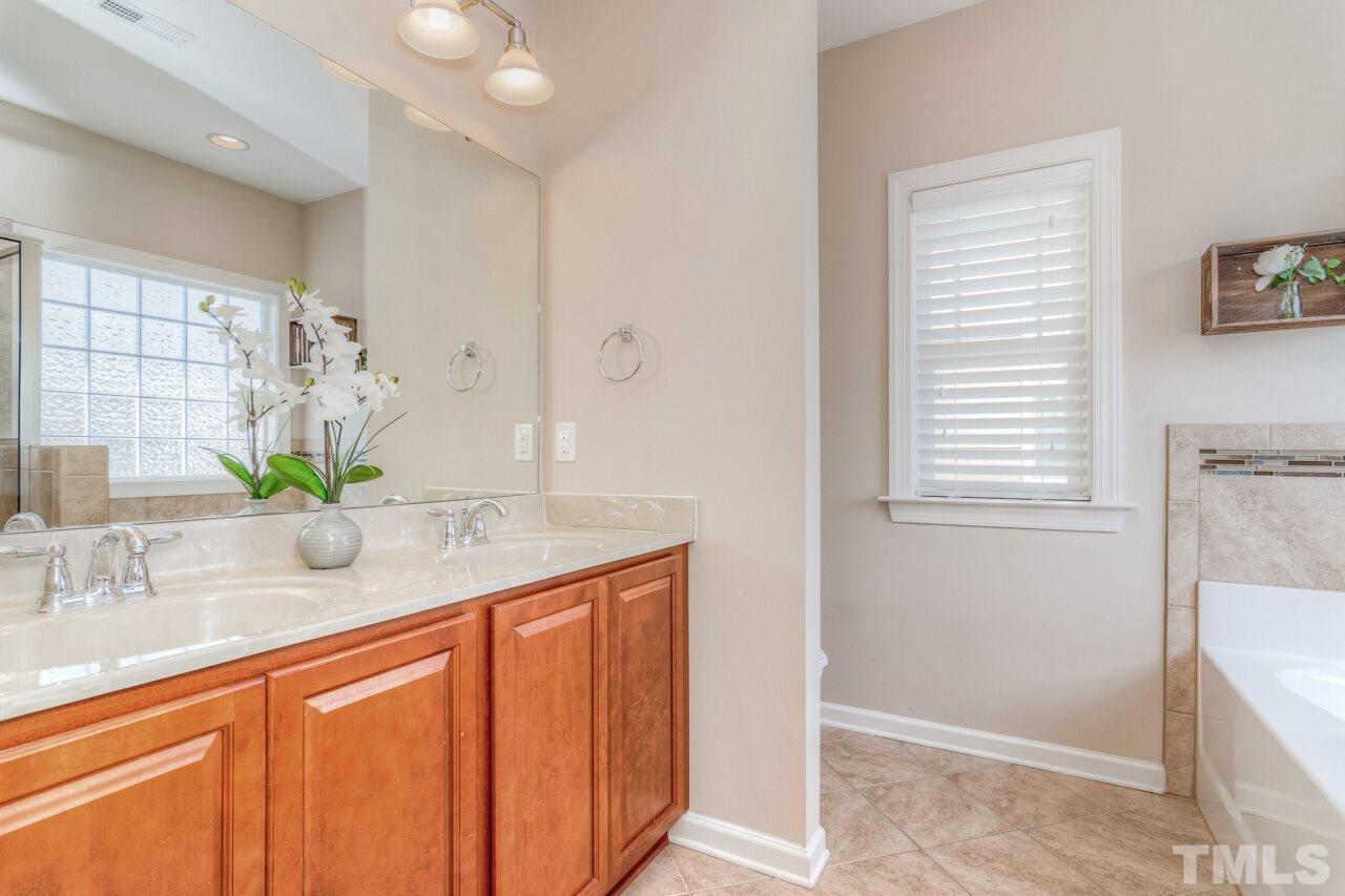 1141 Chapanoke Road Raleigh, NC 27603 - Photo 18 of 25 a bathroom with a granite countertop sink a mirror and a bathtub