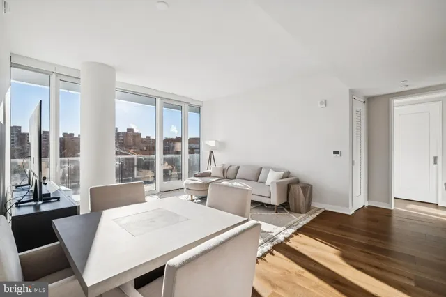 a kitchen with stainless steel appliances a dining table chairs and wooden floor