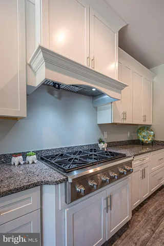 a kitchen with granite countertop a stove and a white cabinets