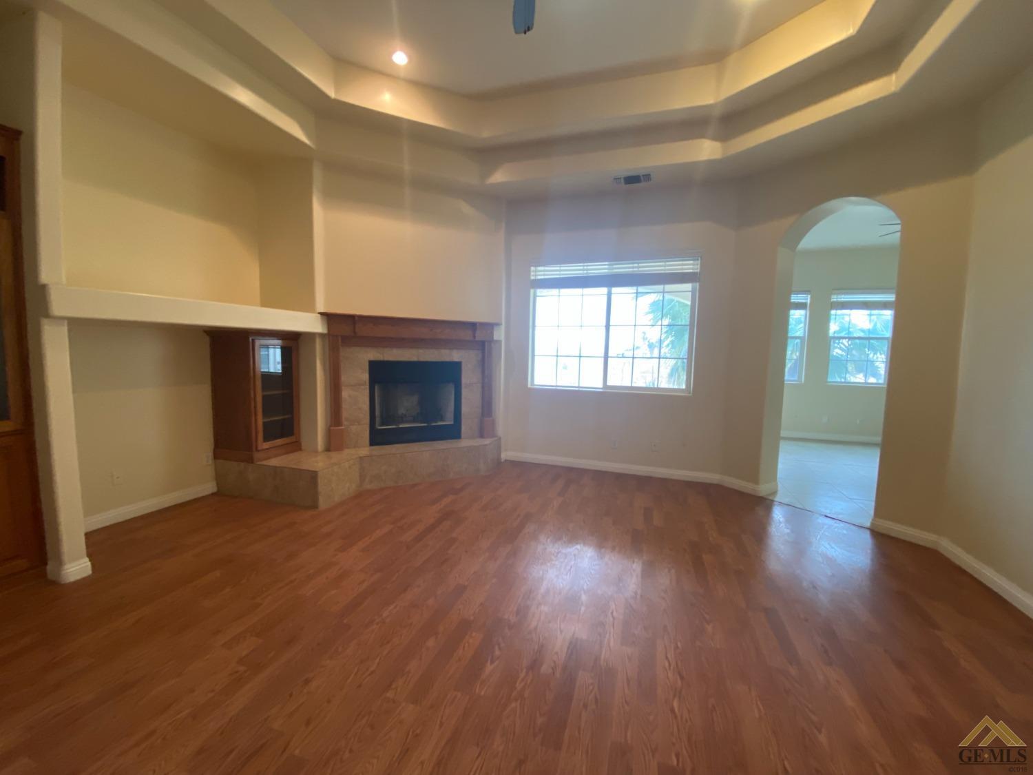 Undisclosed Address Bakersfield, CA 93307 - Photo 11 of 36 an empty room with wooden floor fireplace and windows