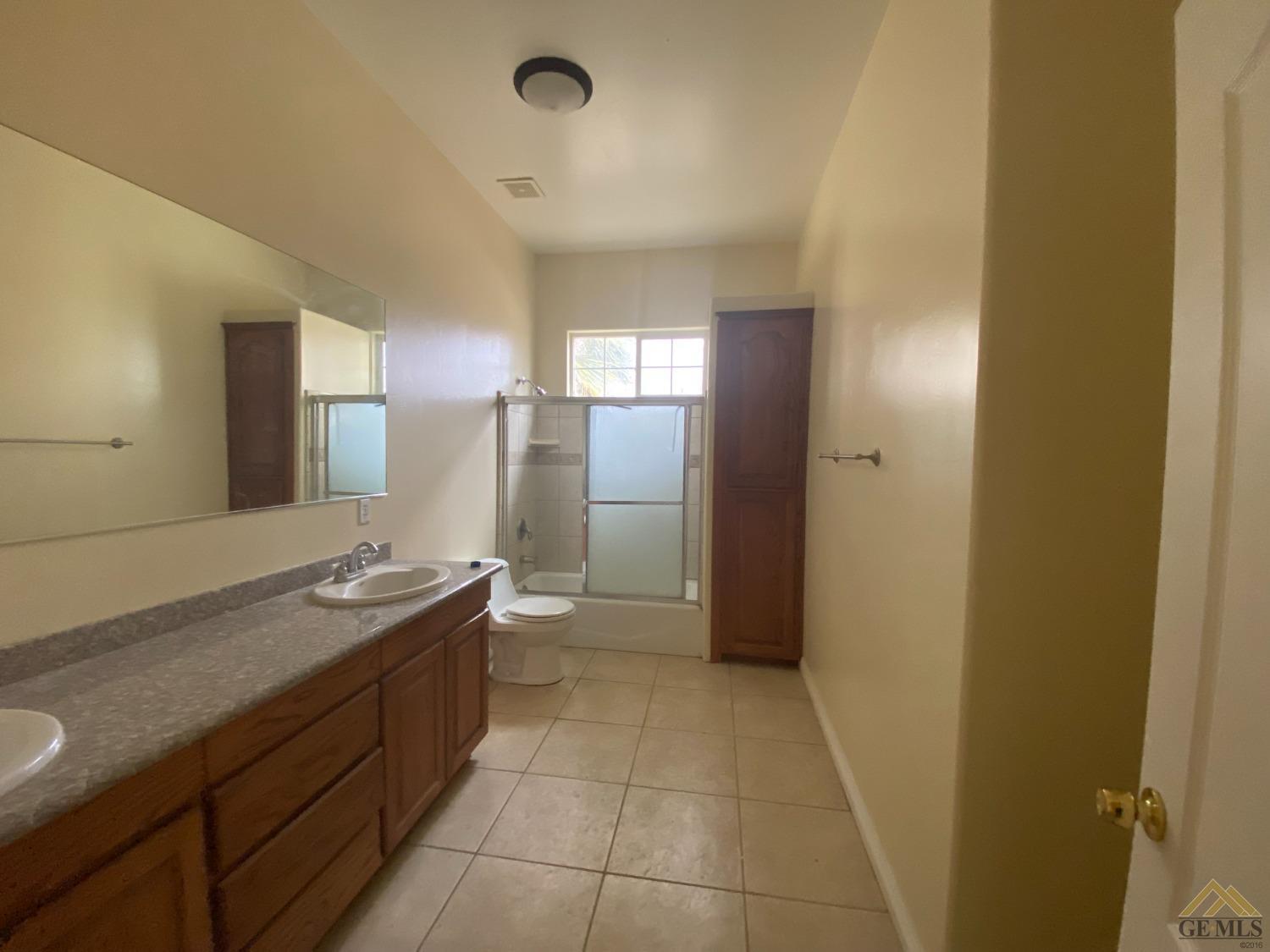 Undisclosed Address Bakersfield, CA 93307 - Photo 15 of 36 a bathroom with a granite countertop sink a toilet and a mirror