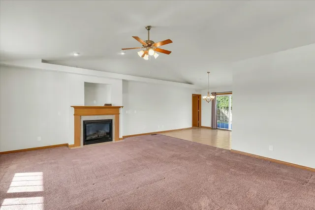 a view of an empty room with window and chandelier fan