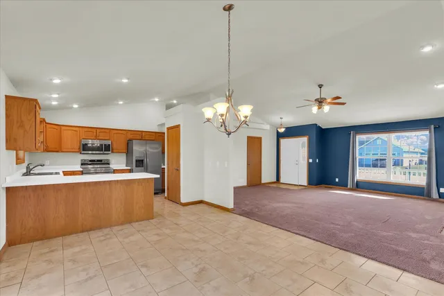 a view of a kitchen with kitchen island a sink chandelier and a living room view