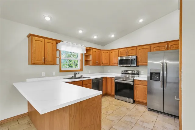 a kitchen with stainless steel appliances granite countertop a sink a stove a refrigerator and blue cabinets with wooden floor