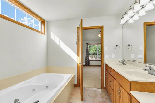 a bathroom with a tub a sink and a large mirror