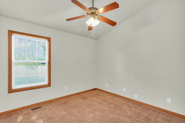 an empty room with a window and a fan
