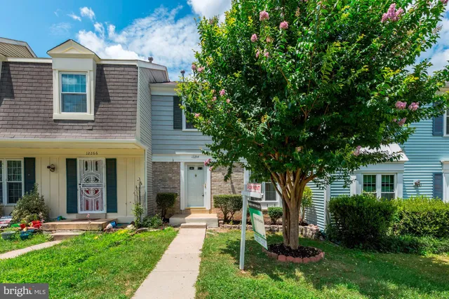 a front view of a house with a yard and potted plants