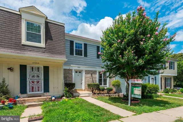 a front view of a house with garden and trees