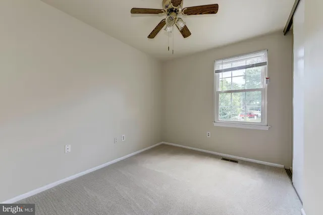 an empty room with a window and a fan