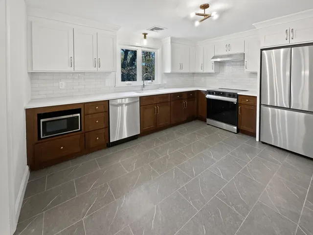a kitchen with stainless steel appliances granite countertop a refrigerator and a stove top oven
