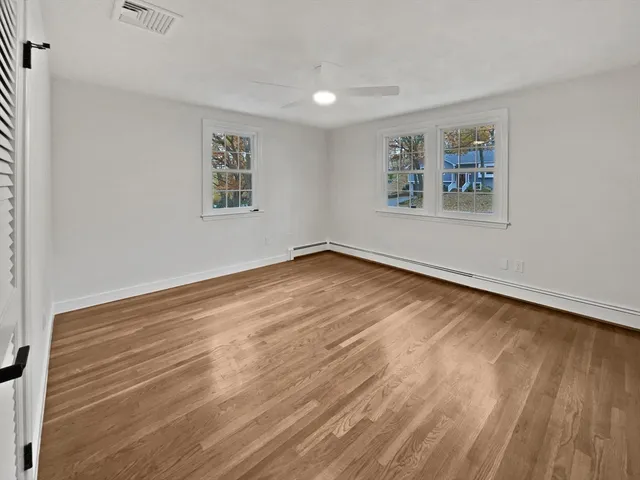 an empty room with wooden floor and windows