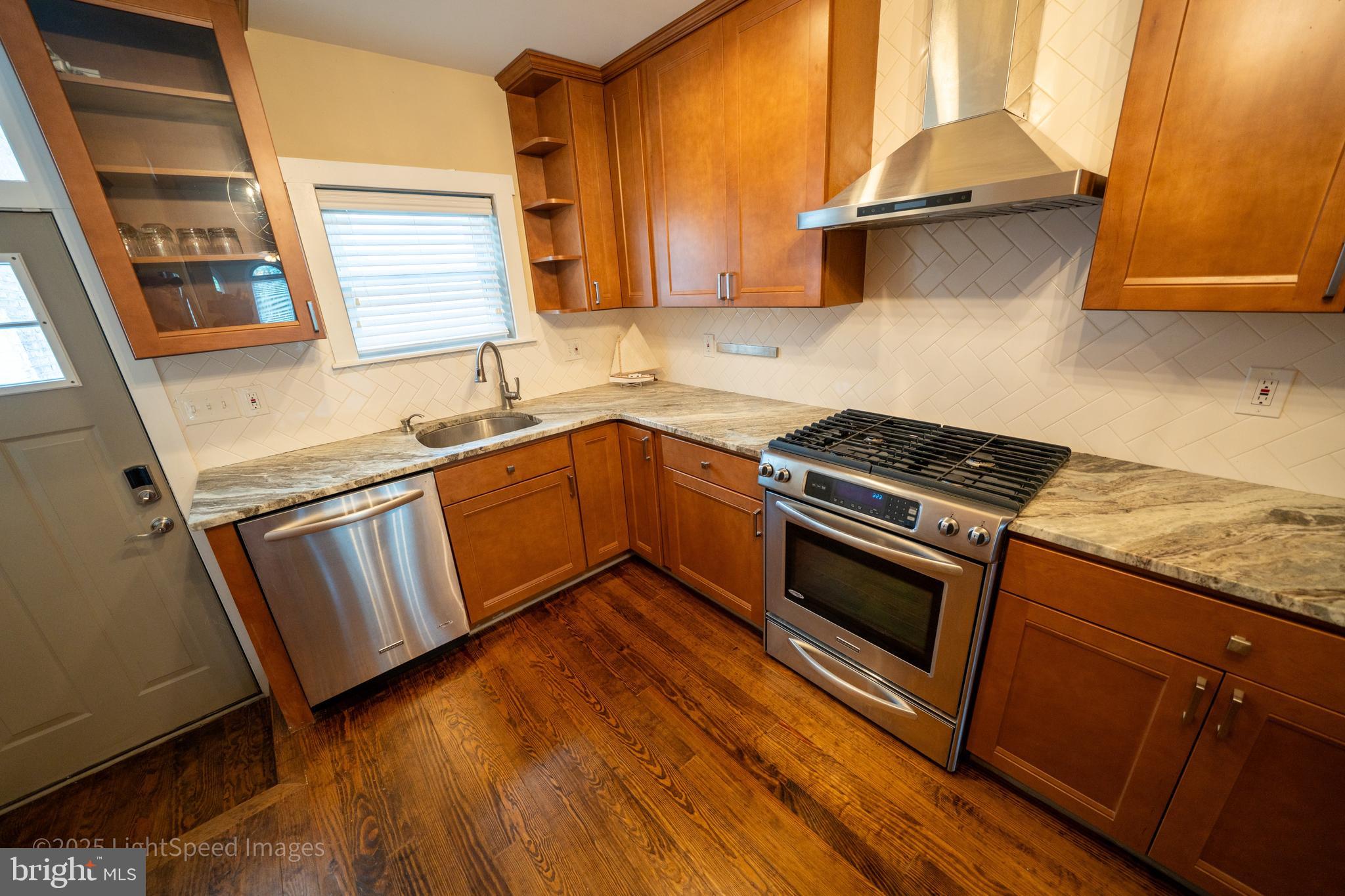 2730 East Baltimore Street Baltimore, MD 21224 - Photo 6 of 40 a kitchen with granite countertop wooden floors and stainless steel appliances