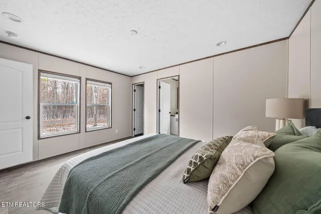 a bedroom with a bed lamp and a large window with outer view