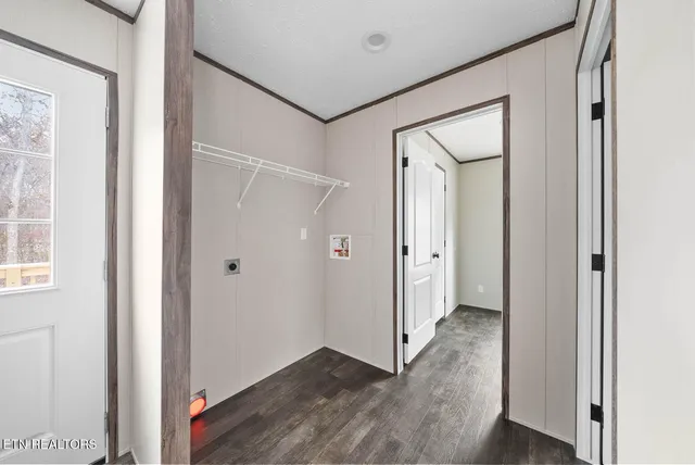 a view of an empty room with wooden floor and a bathroom