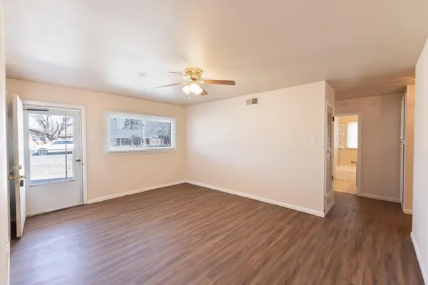 a view of an empty room with a window and wooden floor