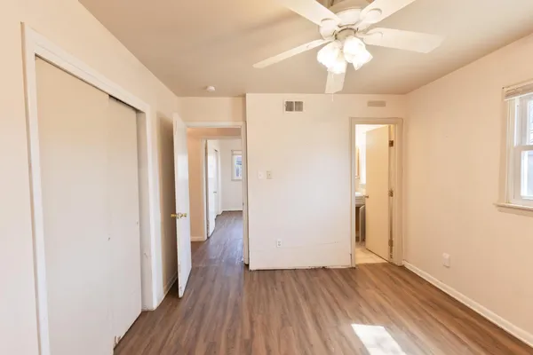 a view of a hallway with wooden floor and a chandelier fan