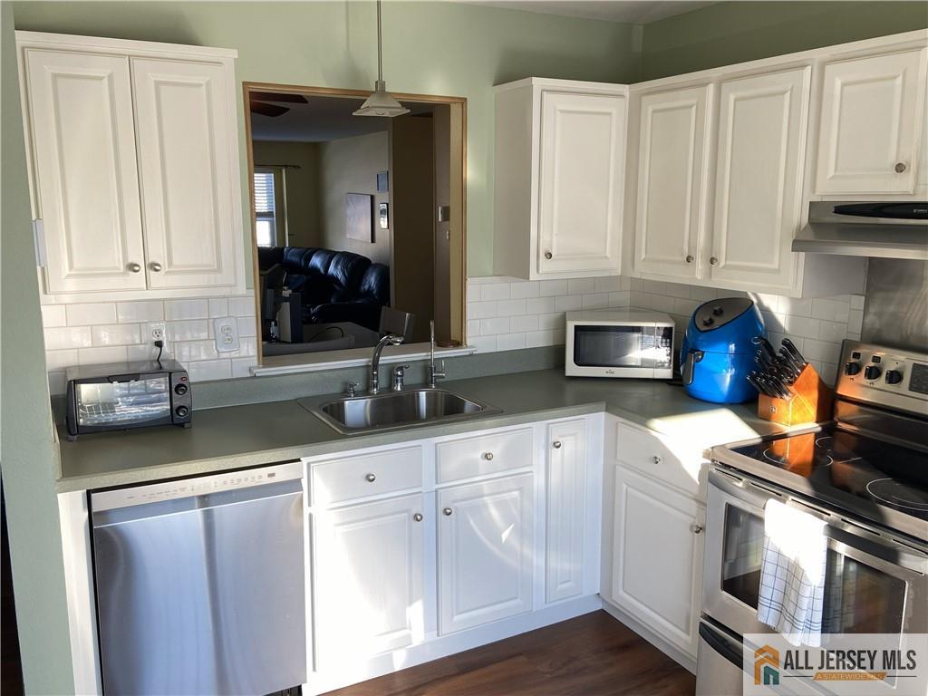 525 Belford Road, Unit O Monroe Township, NJ 08831 - Photo 6 of 19 a kitchen with white cabinets and a stove with wooden floor