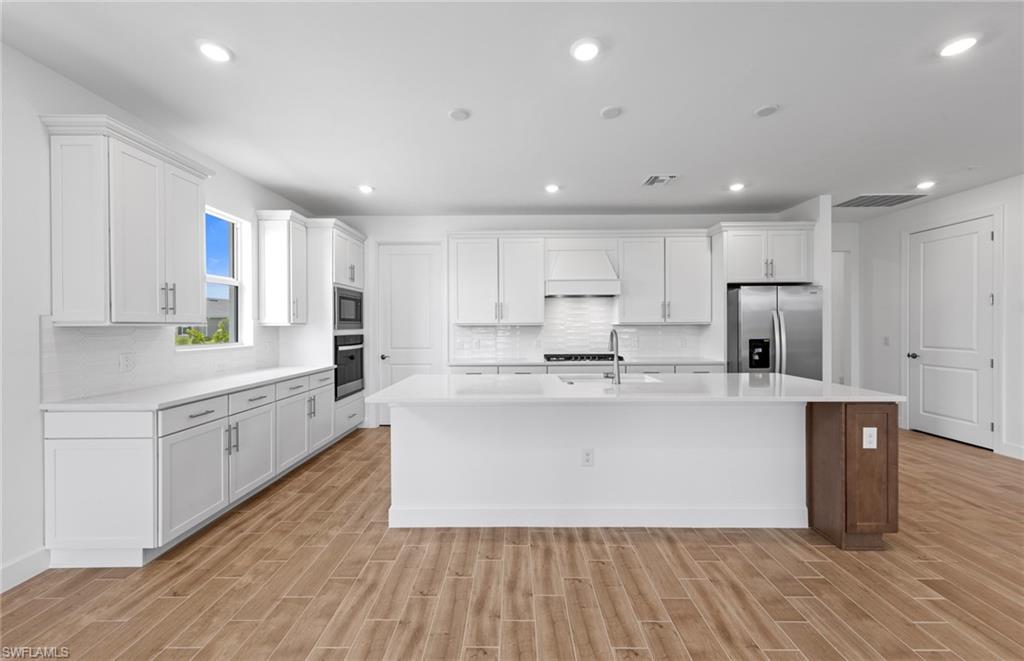 12464 Basalt Lane Alva, FL 33920 - Photo 5 of 28 a large kitchen with kitchen island a sink a center island stainless steel appliances and a counter top space