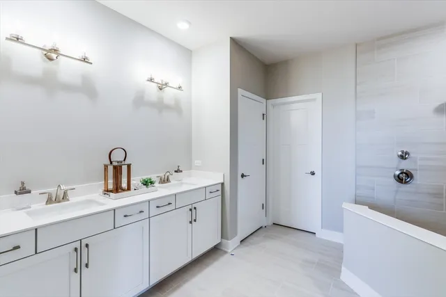 a bathroom with a double vanity sink a large mirror and a bathtub