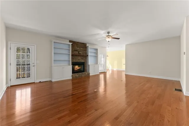 an empty room with chandelier fan and windows