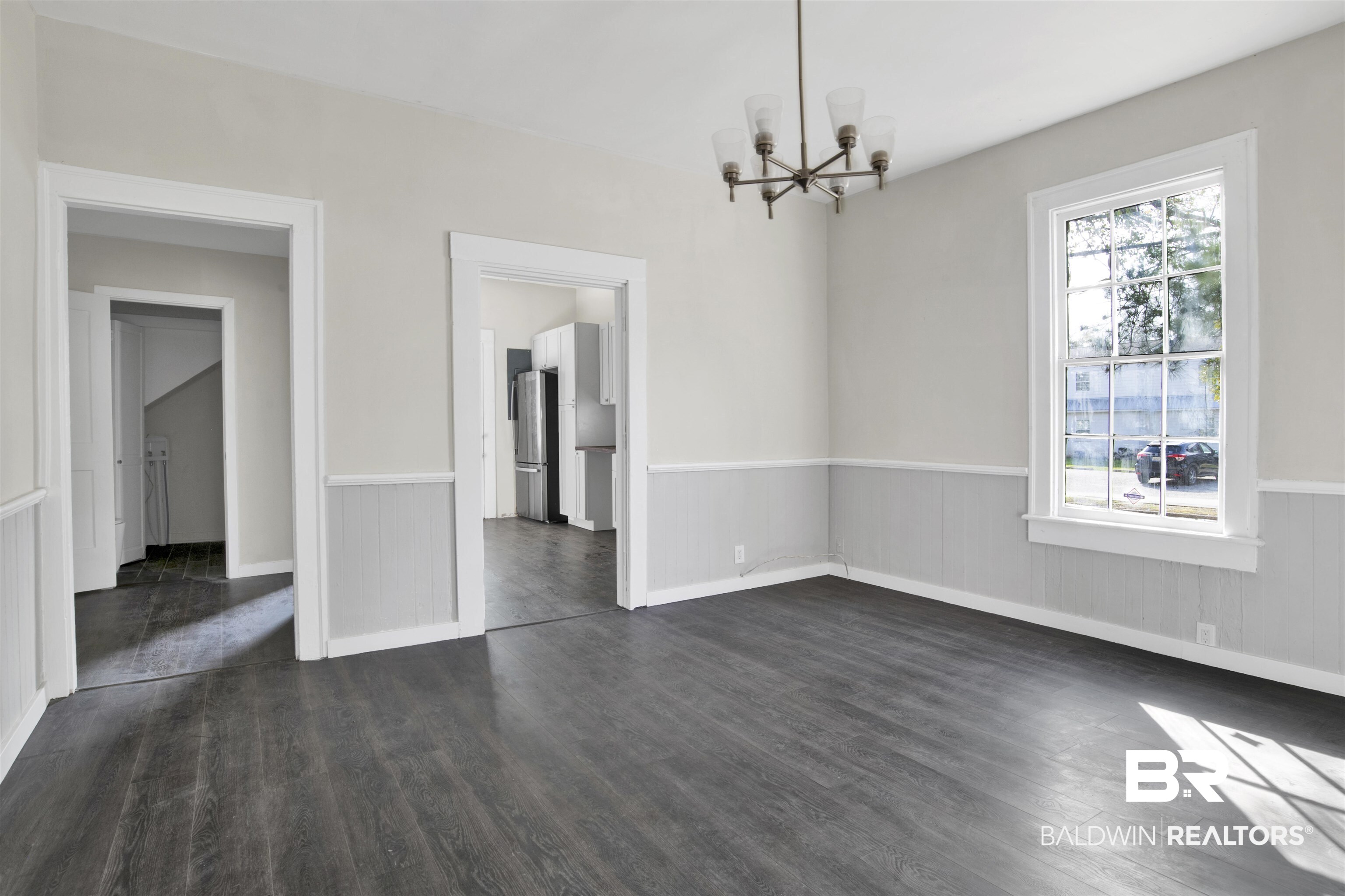 1063 Selma Street Mobile, AL 36604 - Photo 10 of 32 Unfurnished dining area featuring hanging lights, dark wood-style flooring, and a wainscoted wall