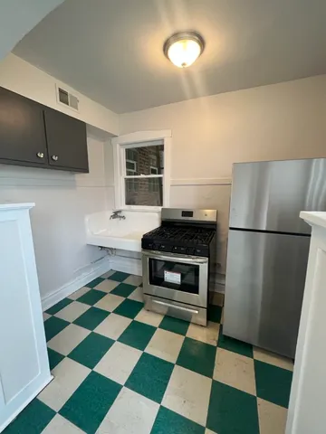 a kitchen with a checkered floor and a black refrigerator