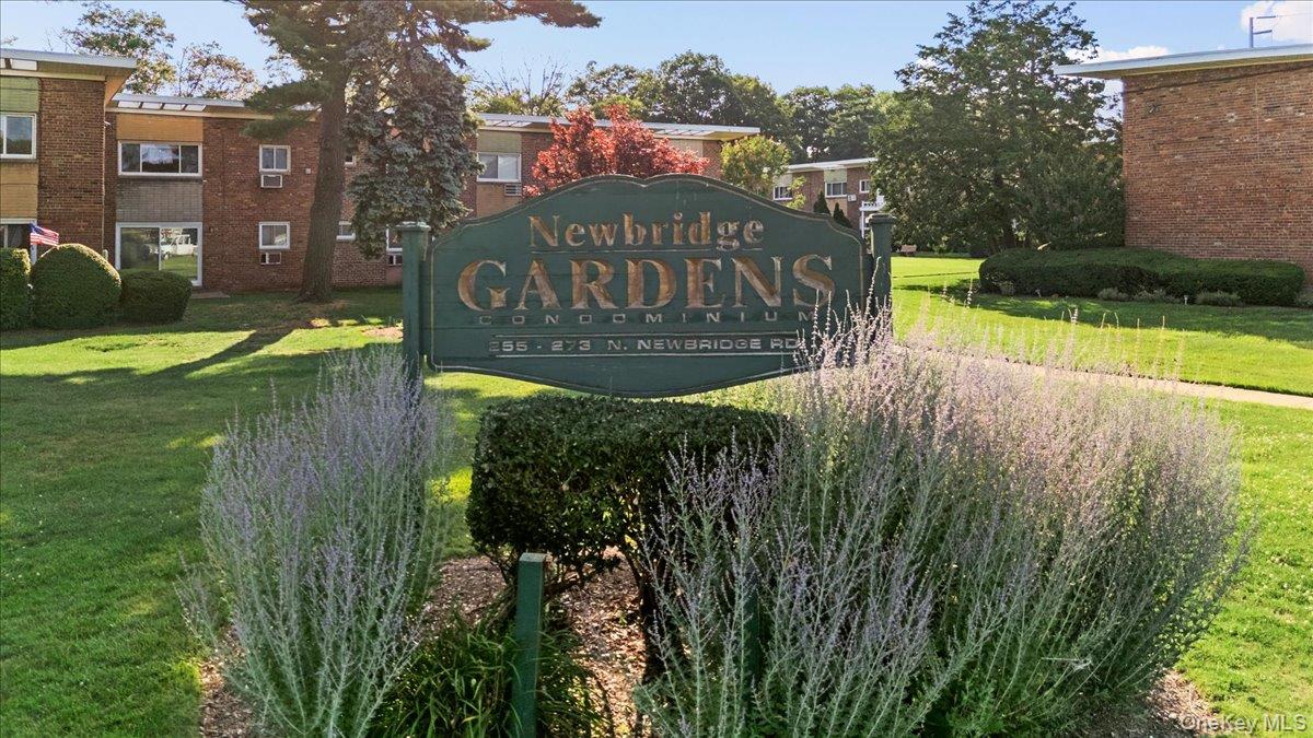 267 North Newbridge Road, Unit 2D Levittown, NY 11756 - Photo 21 of 22 Newbridge Gardens Condominium entrance sign, featuring mature landscaping and brick-exterior buildings