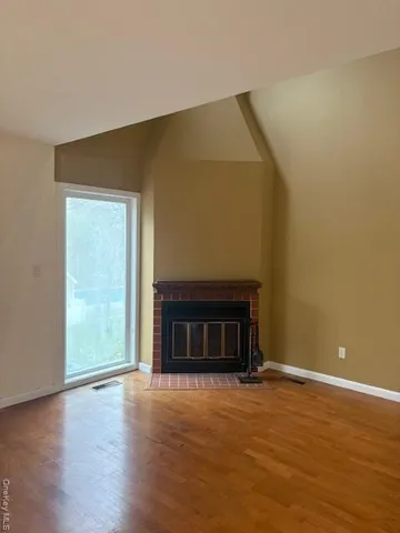 a view of empty room with wooden floor and fireplace