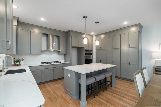 a large kitchen with a center island wooden floor stainless steel appliances and cabinets