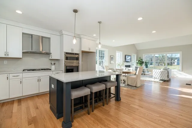 a kitchen with stainless steel appliances granite countertop a stove a sink dishwasher a dining table and chairs with wooden floor