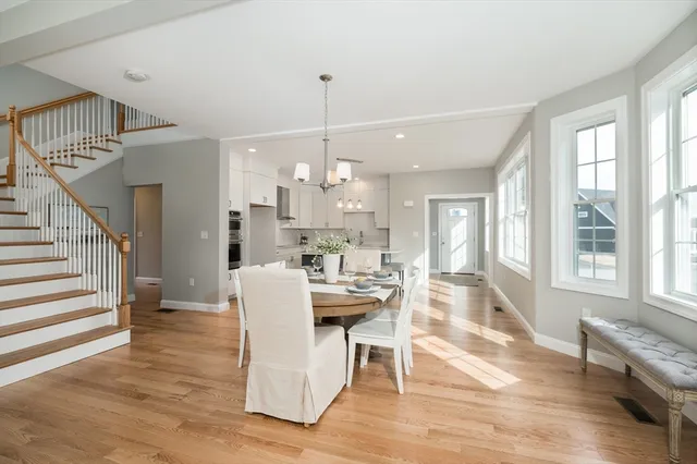 a view of a dining room and livingroom with furniture wooden floor windows and a chandelier