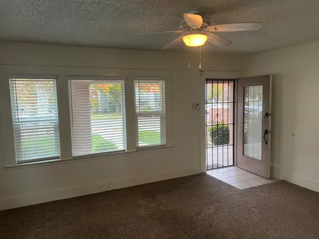 a view of an empty room with window and chandelier fan