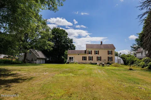 a view of a house with a big yard and large trees